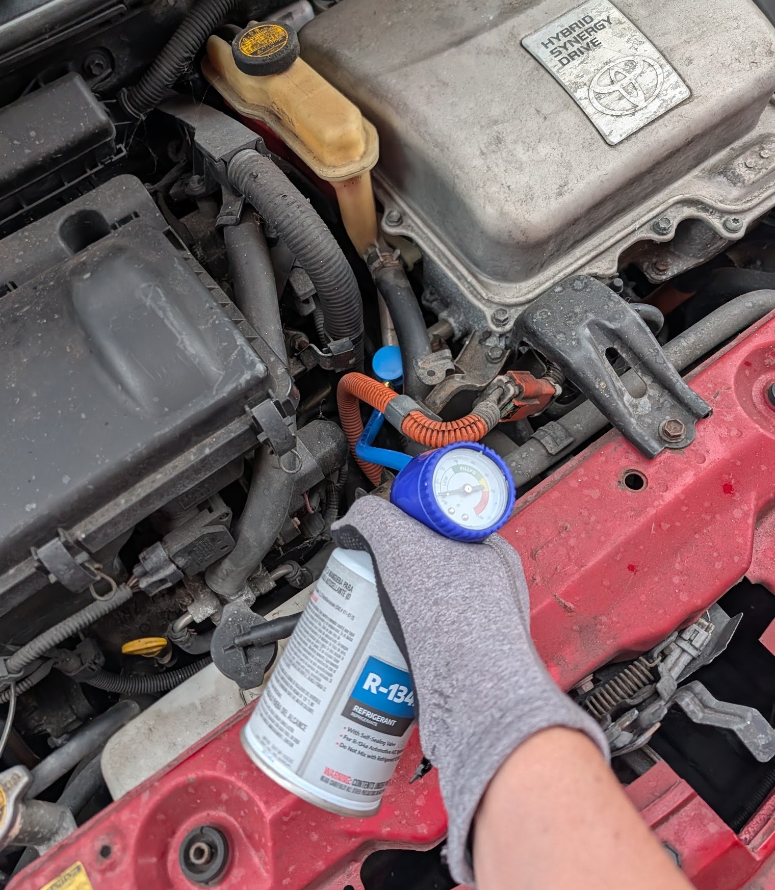 AC recharge hose connected to low-side port with engine on and gauge showing very low pressure